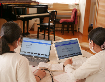 パソコンで音楽を作る女子2人の写真