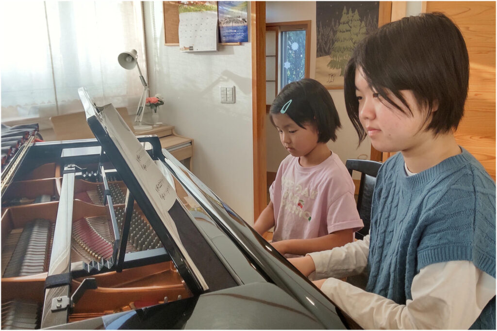 姉妹で並んでピアノを弾いている写真